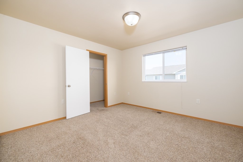 A room with a carpeted floor, a door, and a window.