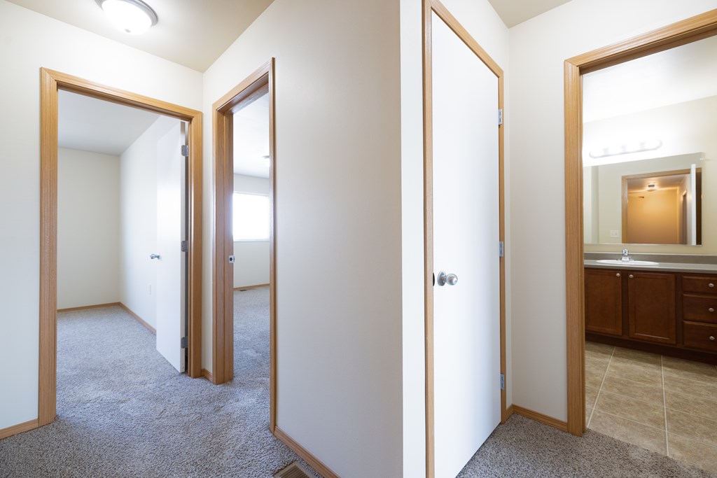 A hallway with a carpeted floor and white walls.