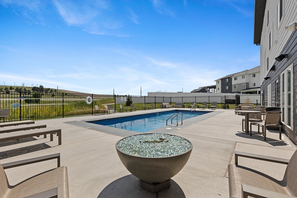 A pool with a fountain in the middle of a patio.