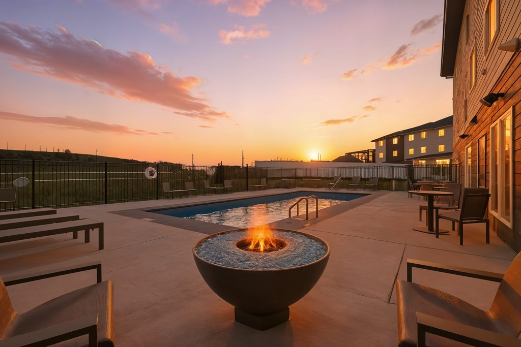 A fire pit sits in the middle of a patio with chairs around it.