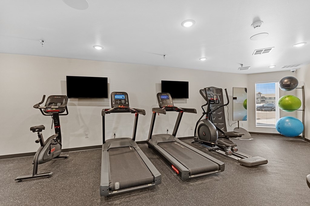 A gym with treadmills, exercise bikes, and a television.