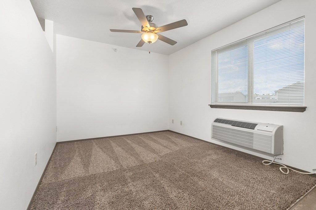A room with a ceiling fan and a window with blinds.