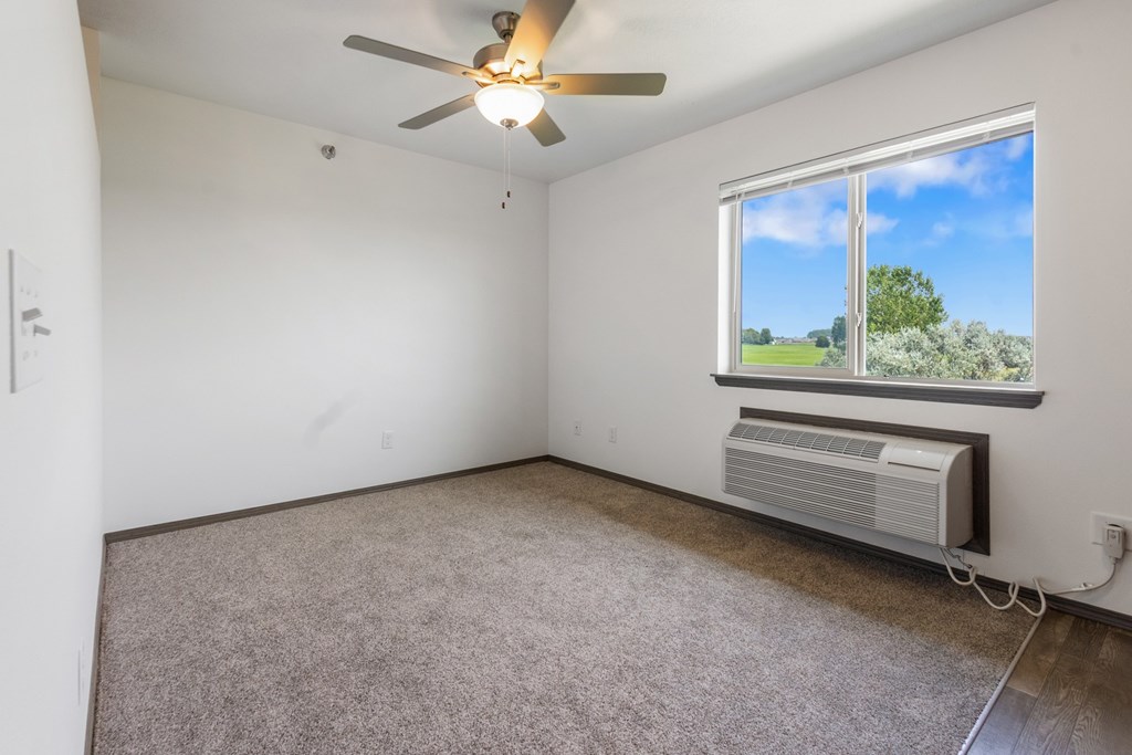 A room with a ceiling fan and a window showing a view of the outside.
