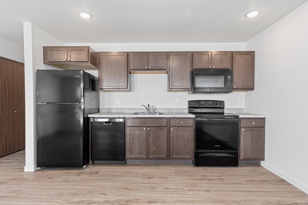 an empty kitchen with black appliances and wooden cabinets