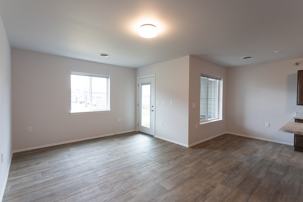 an empty living room with wood floors and a window