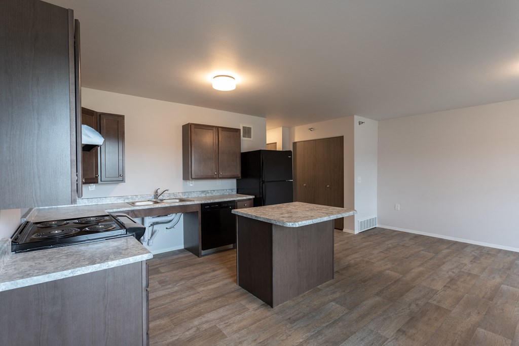 an empty kitchen with stainless steel appliances and wood flooring