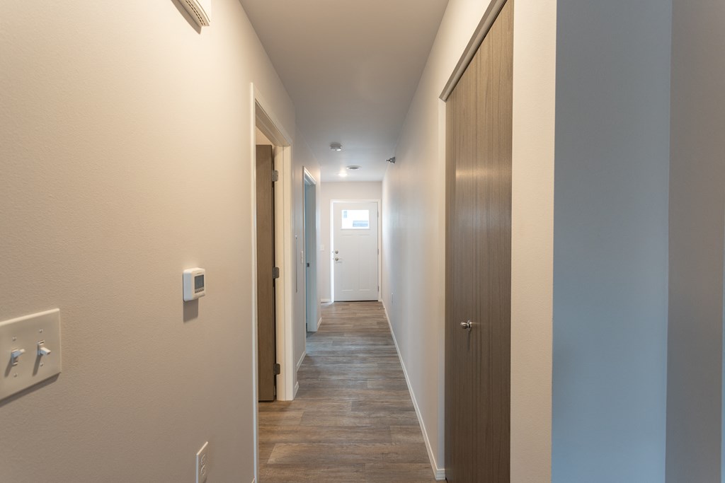 a long hallway with a door to a bedroom and a hallway leading to a bathroom