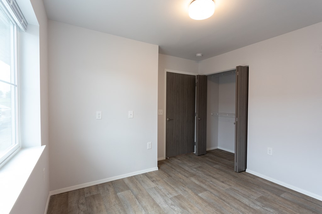 an empty living room with white walls and a door to a closet