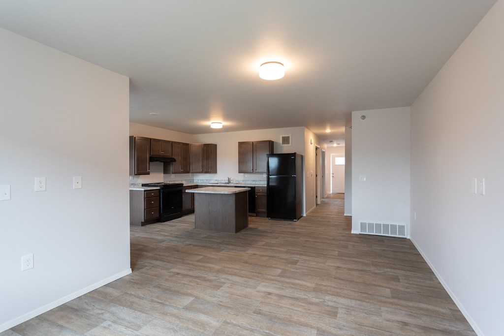 a kitchen and living room with white walls and wood flooring