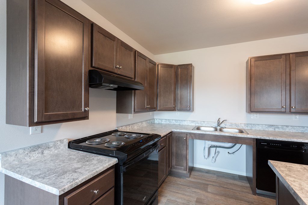 an empty kitchen with dark wood cabinets and granite counter tops