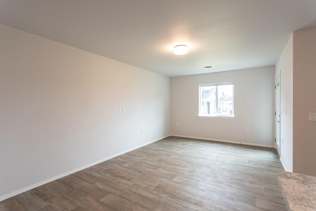 an empty living room with white walls and a window