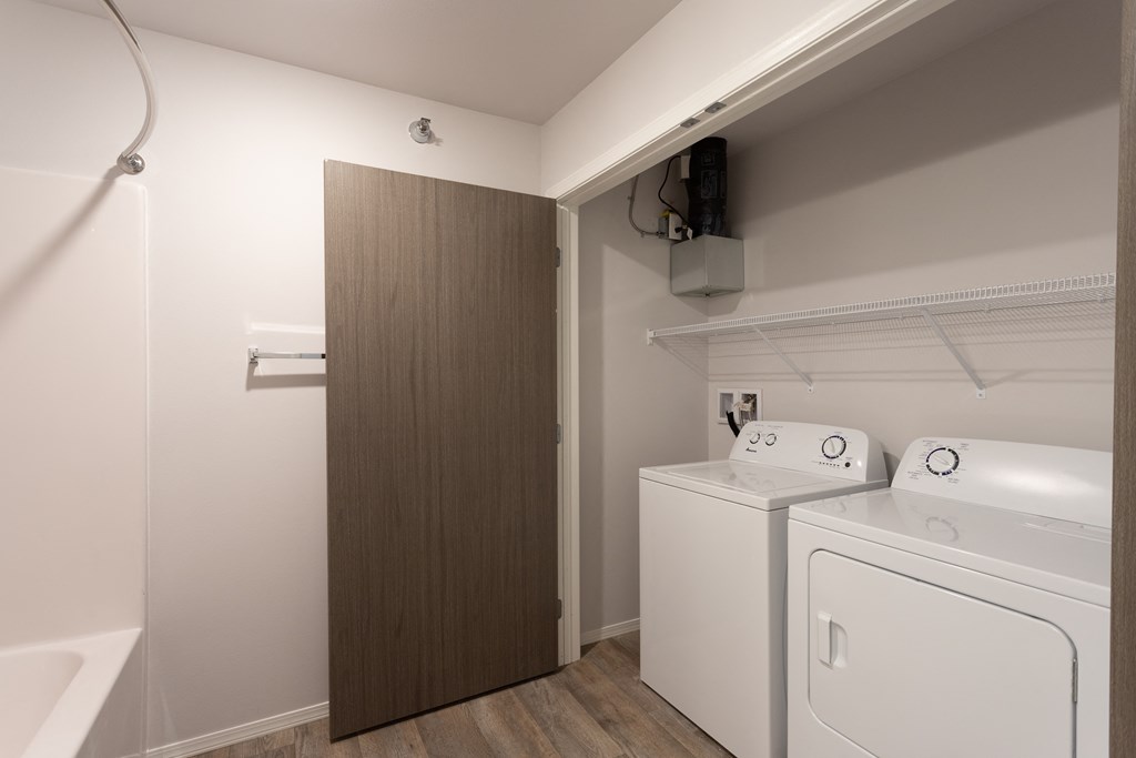 a laundry room with a washer and dryer and a door to a bathroom