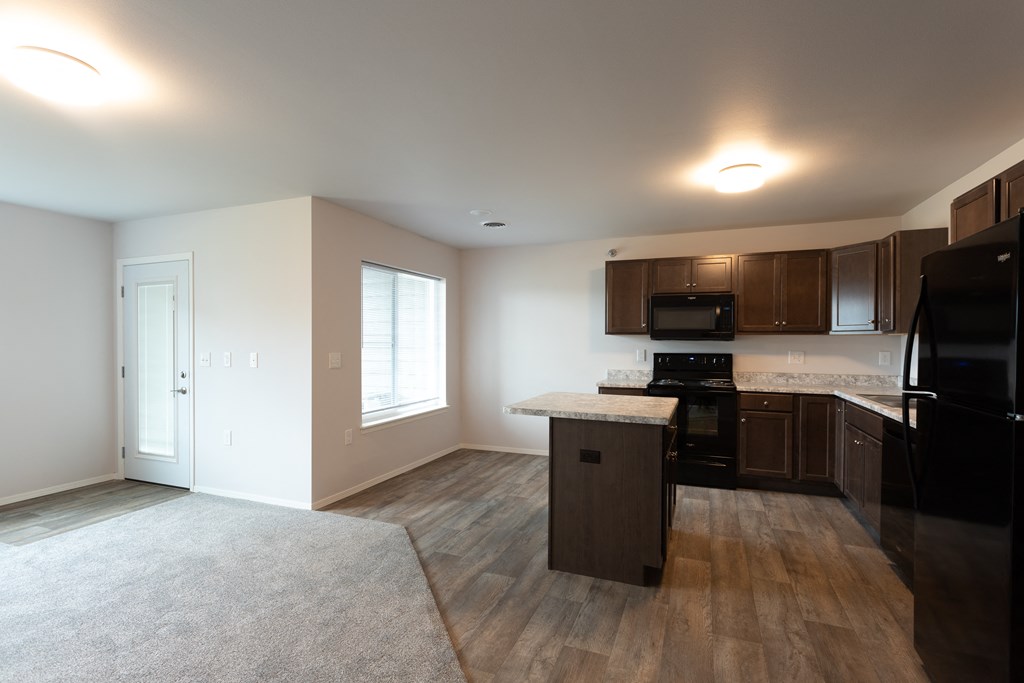 an empty kitchen with black appliances and wooden cabinets