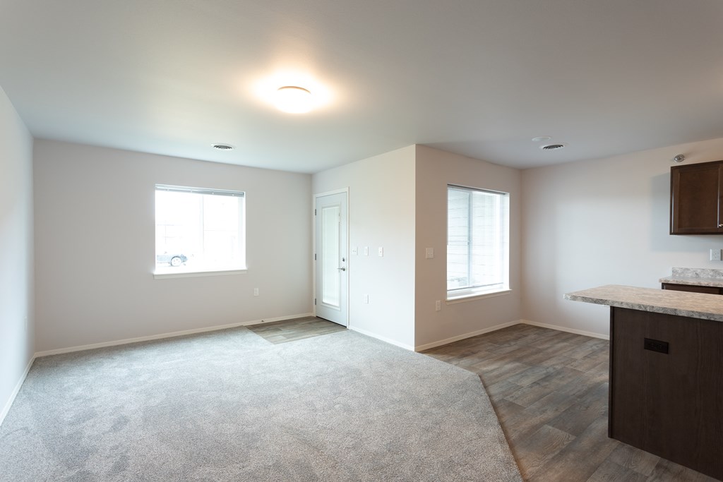 an empty kitchen and living room with a door and window