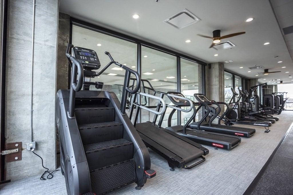 a gym with cardio equipment and glass windows