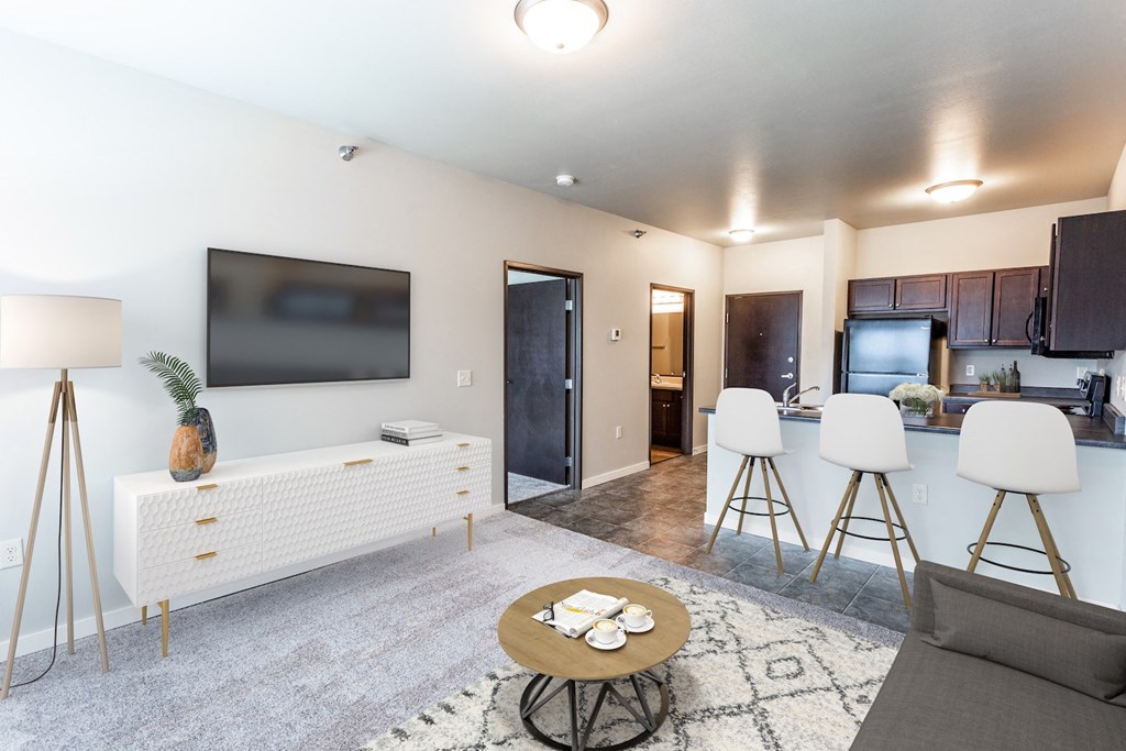 a living room with a tv and a kitchen with a table and chairs