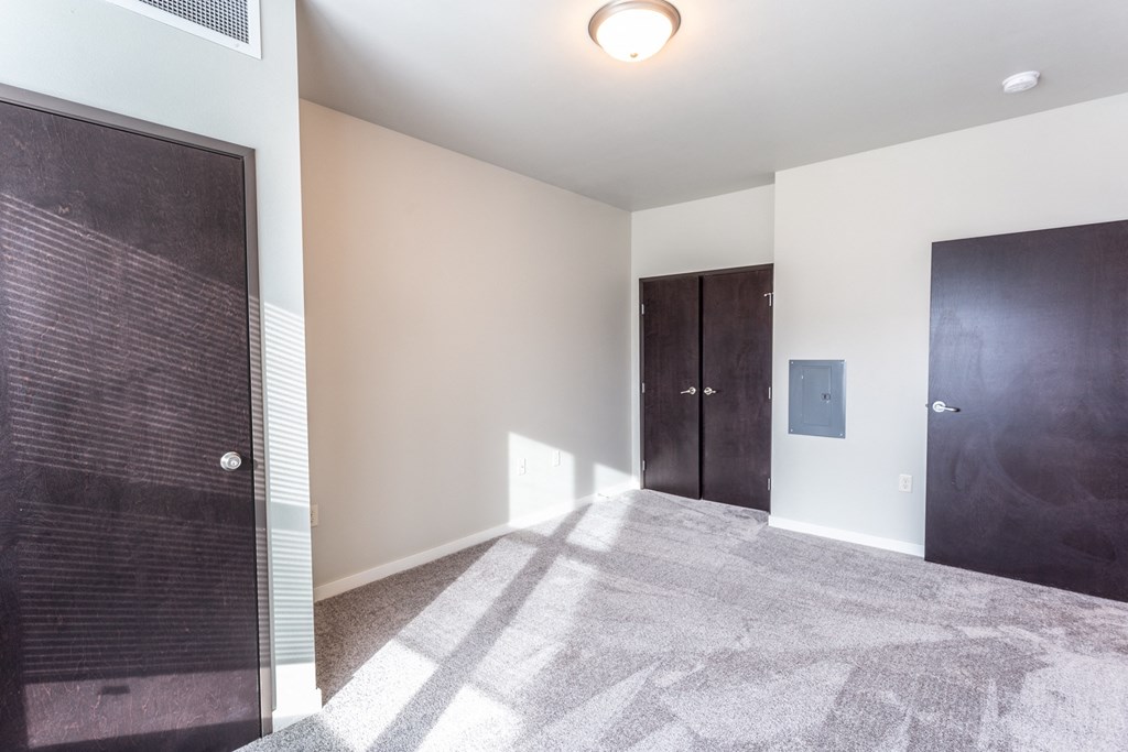 an empty room with a door to a closet and a carpeted floor