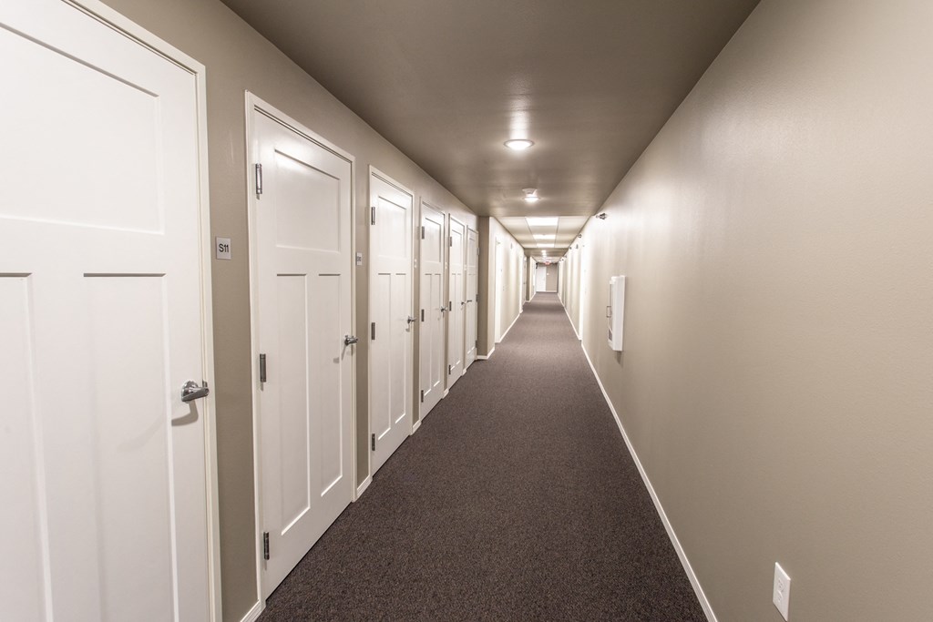 a long hallway with white doors in a hotel room