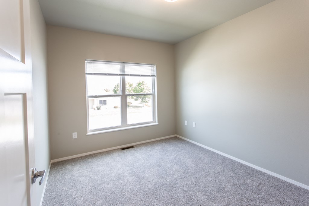an empty room with a large window and carpet