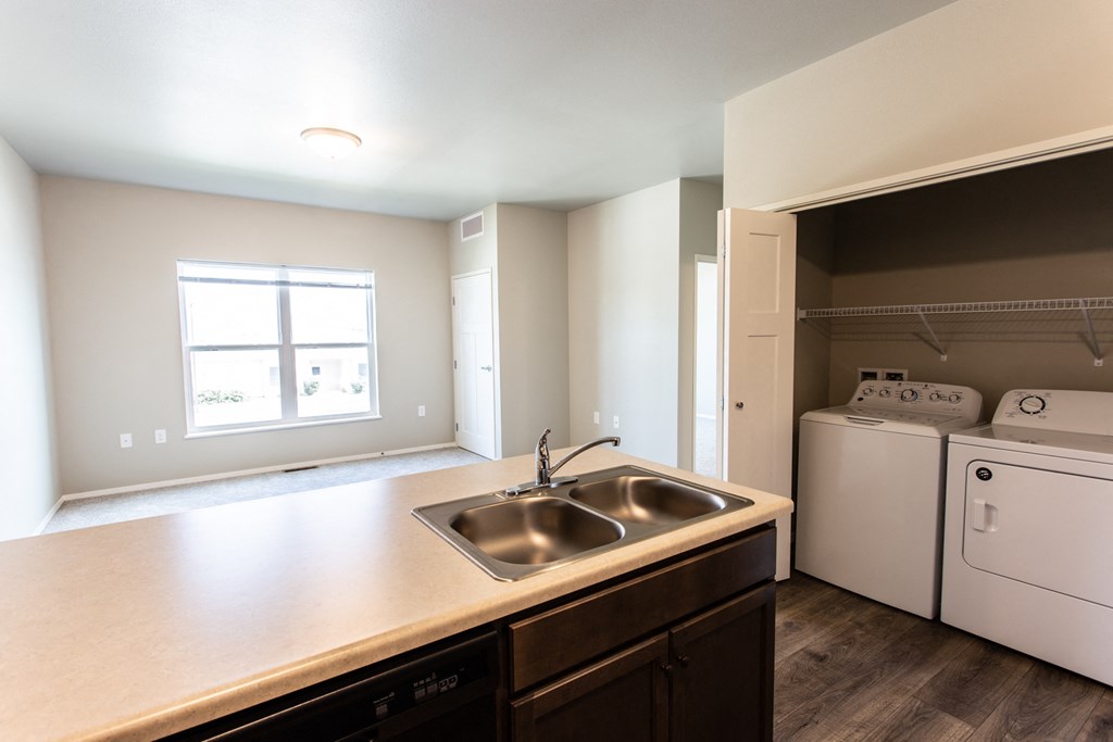 an empty kitchen with a sink and a washer and dryer