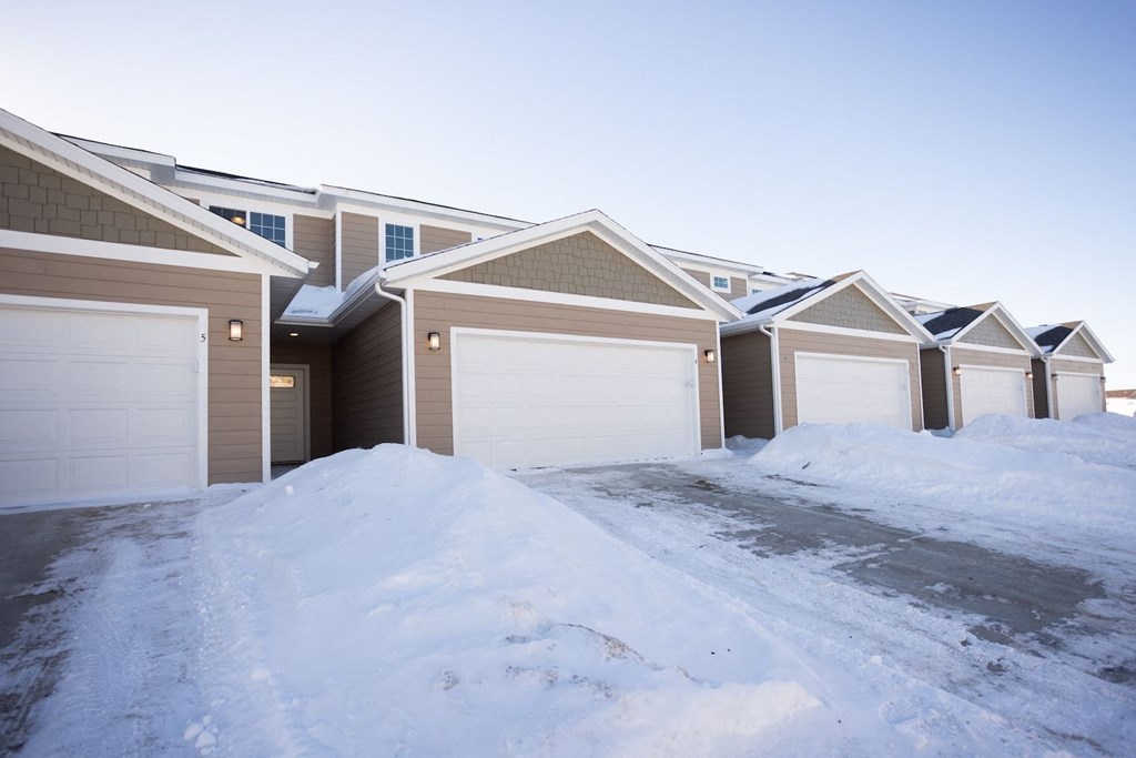 a row of houses with garage doors covered in snow