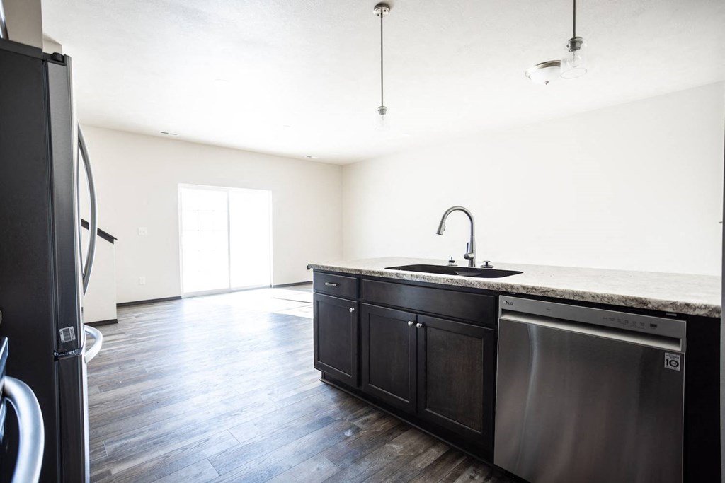 a kitchen with black cabinets and a sink and a refrigerator
