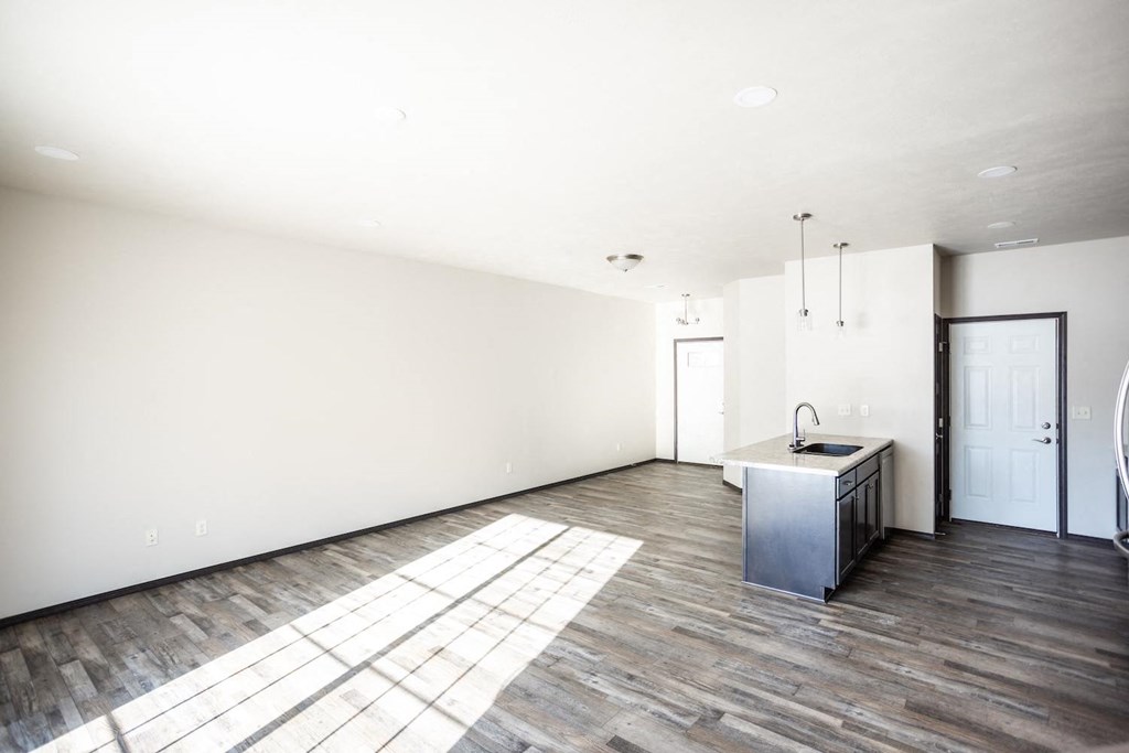 the living room and kitchen of a new home with white walls and wood floors