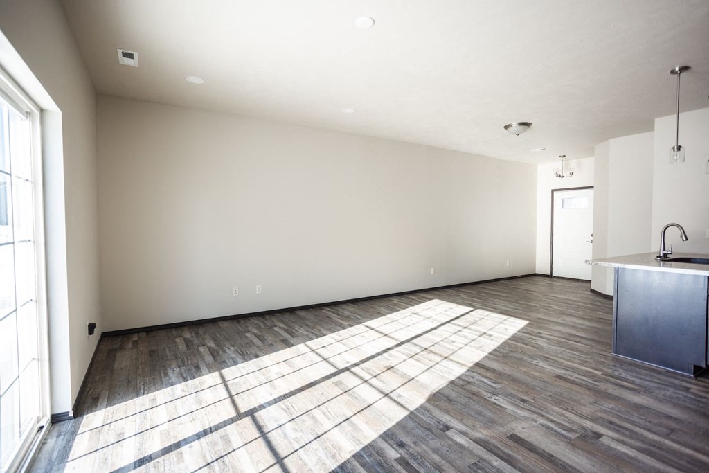 the living room and kitchen of a new home with wood floors and white walls