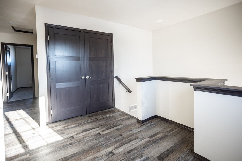a room with white walls and a black door and a staircase
