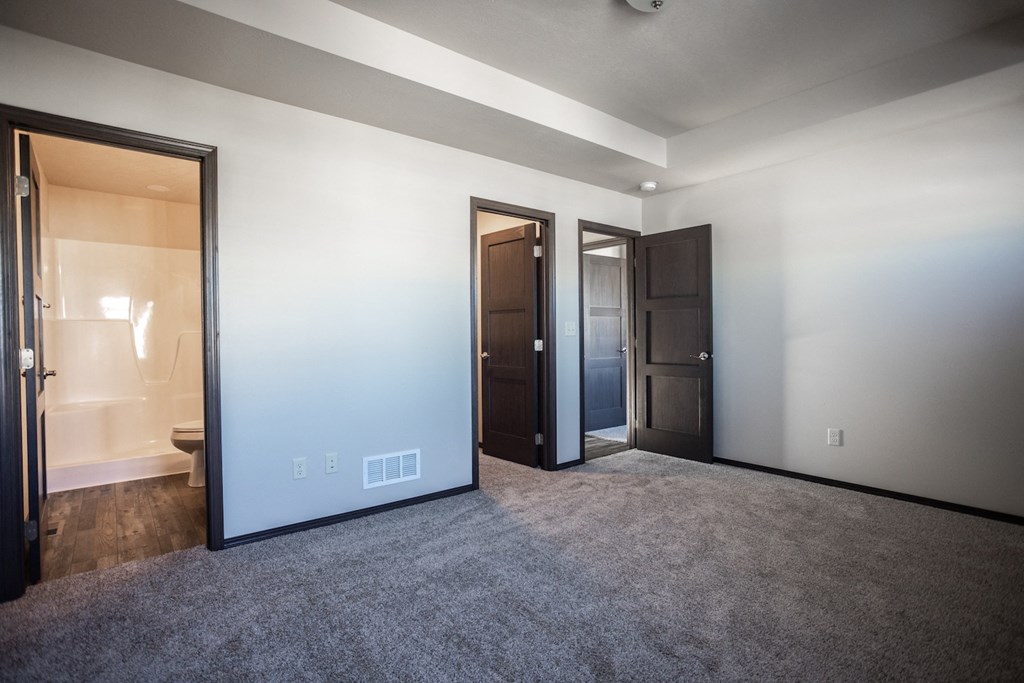 an empty living room with a door to a bathroom and a closet