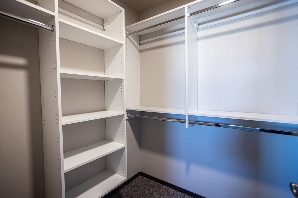 a walk in closet with white shelves and a blue door