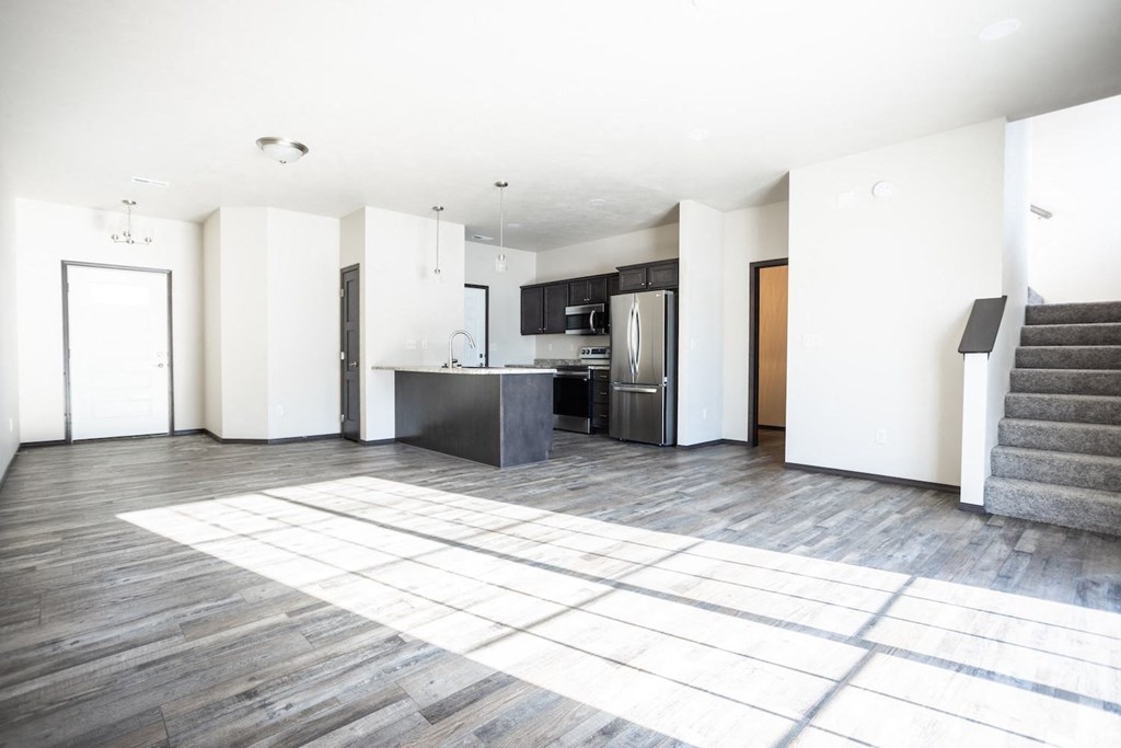 an empty living room with a kitchen and stairs