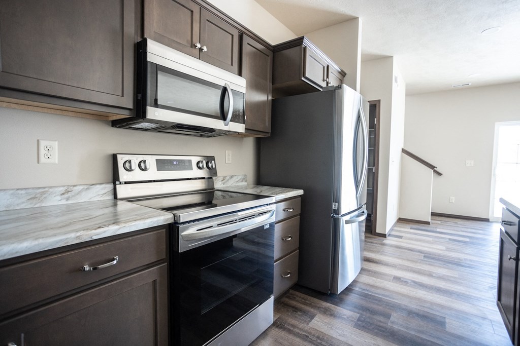 an empty kitchen with stainless steel appliances and wooden floors