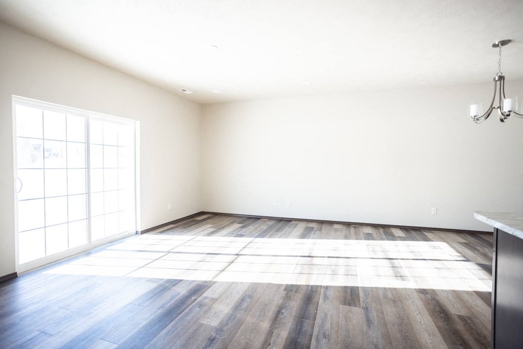 an empty living room with wood floors and a window