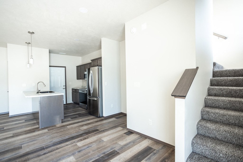a renovated living room with stairs and a kitchen with stainless steel appliances