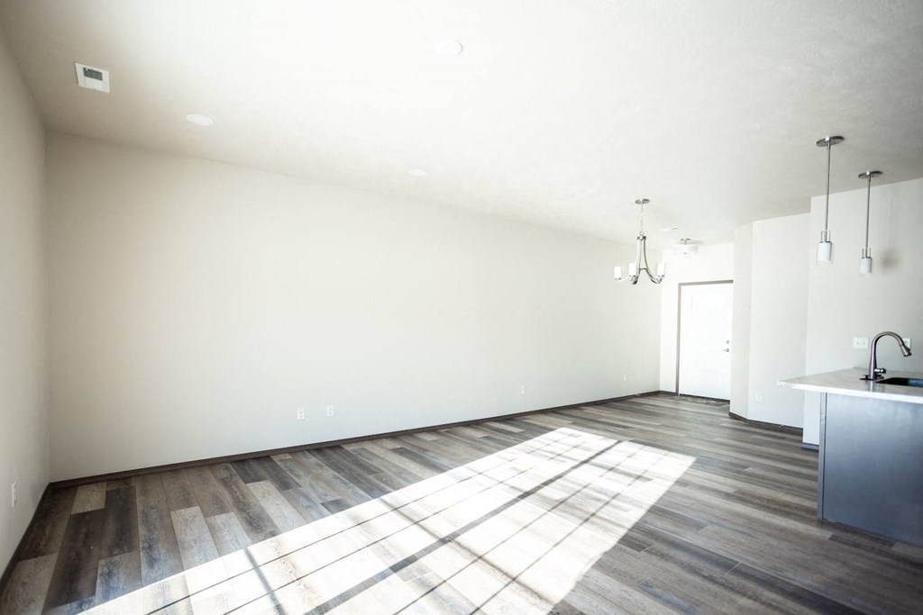 the living room and kitchen of a new home with wood floors and white walls
