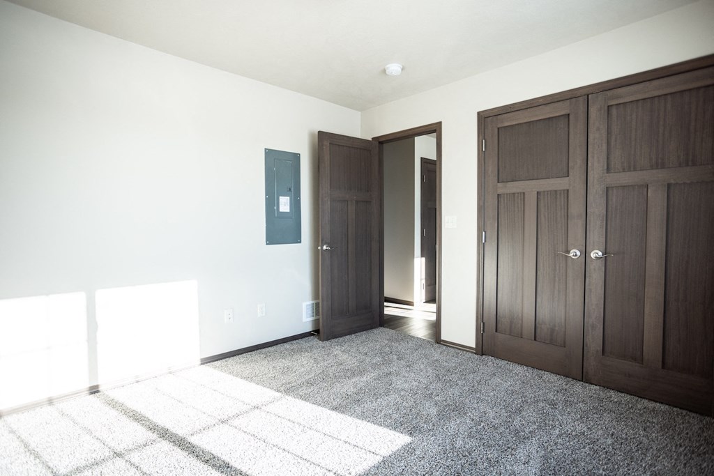 an empty room with two doors and a carpeted floor