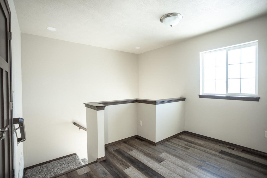 an empty room with wood flooring and a window