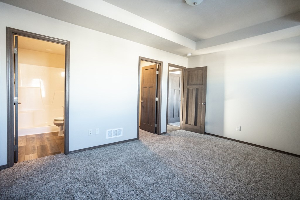 an empty living room with three doors and a carpeted floor