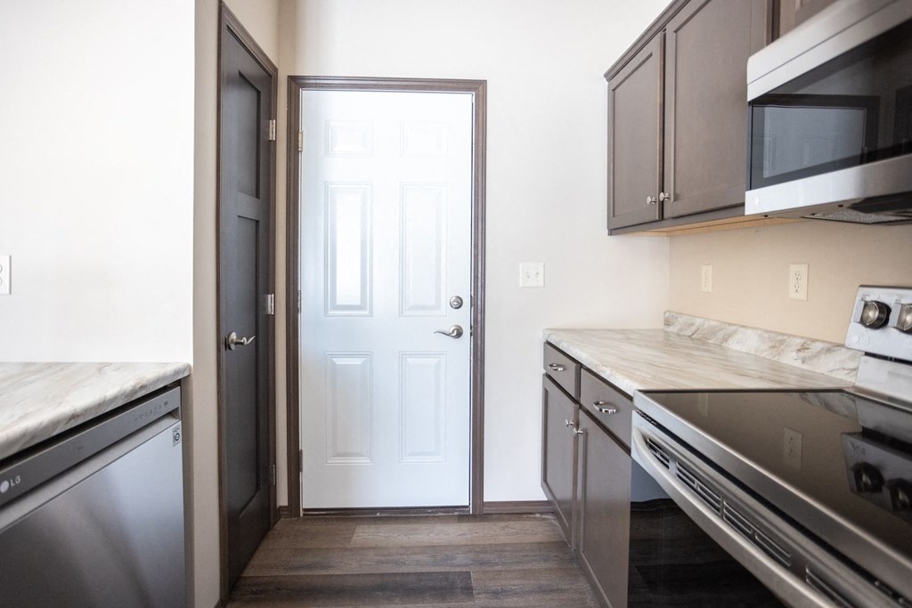 a small kitchen with stainless steel appliances and a white door