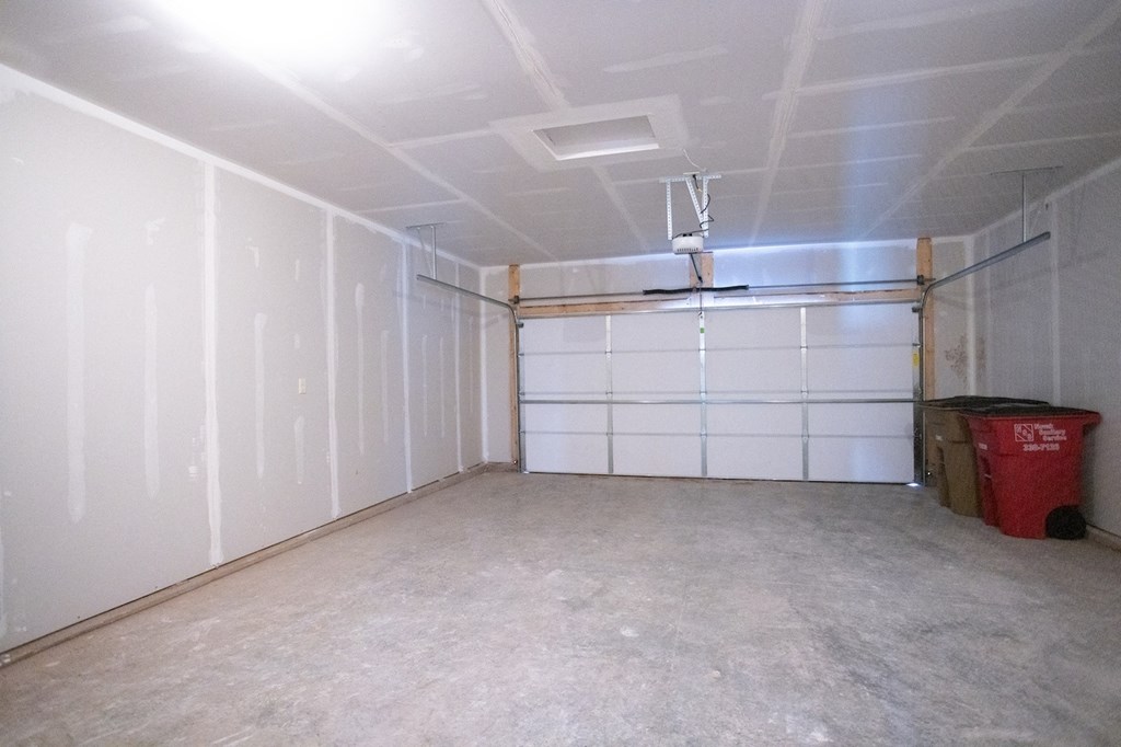 a garage with a white wall and a red trash can