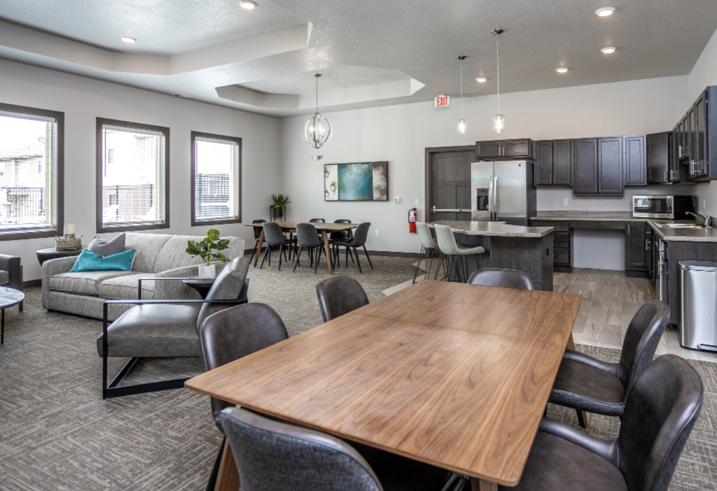 Spacious community room with fireplace, kitchen, and lounge seating.