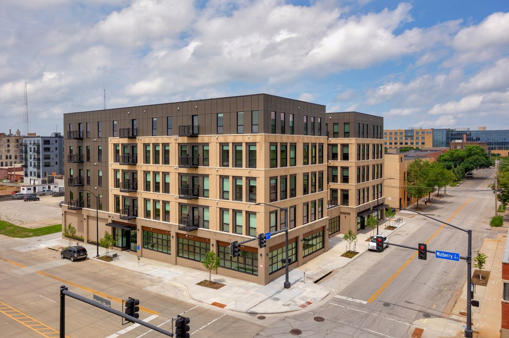 A street view of a multi-story building with a traffic light in front of it.