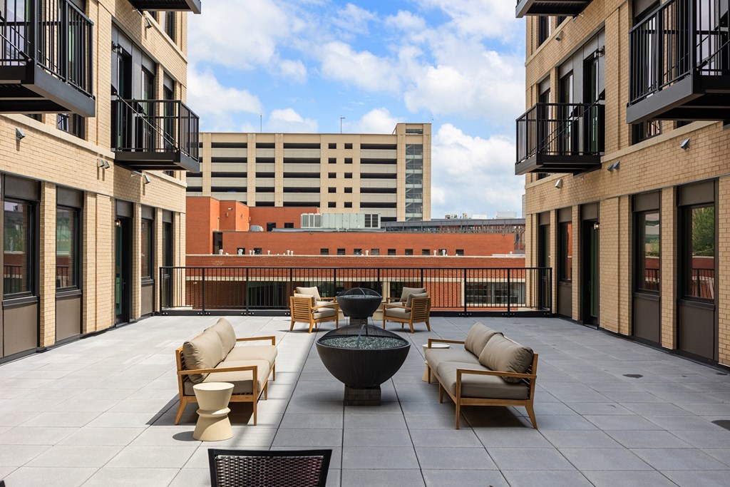 A patio with chairs and a table is surrounded by buildings.