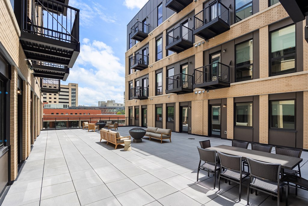 A patio with a table and chairs is surrounded by balconies.