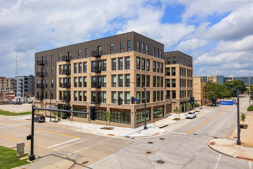 A large building with many windows is situated on a street corner.