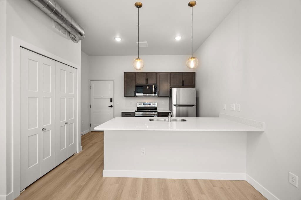 A kitchen with white cabinets and a white island with a sink.