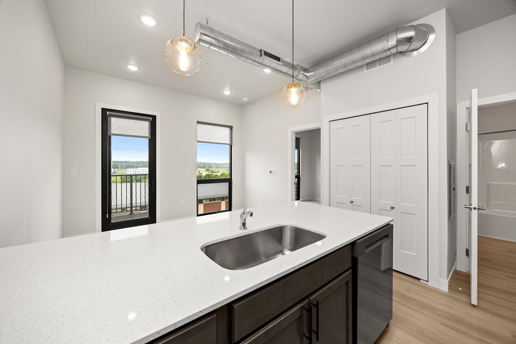 A modern kitchen with a white countertop and a stainless steel sink.