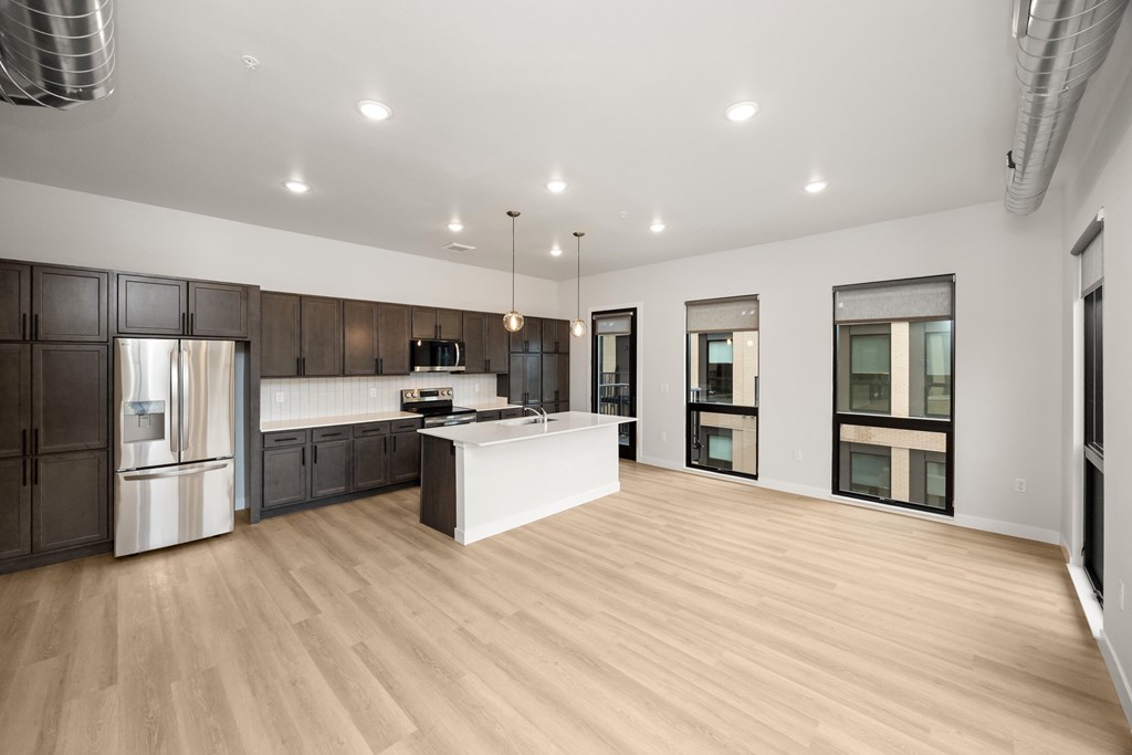 A modern kitchen with wooden floors and a white island.