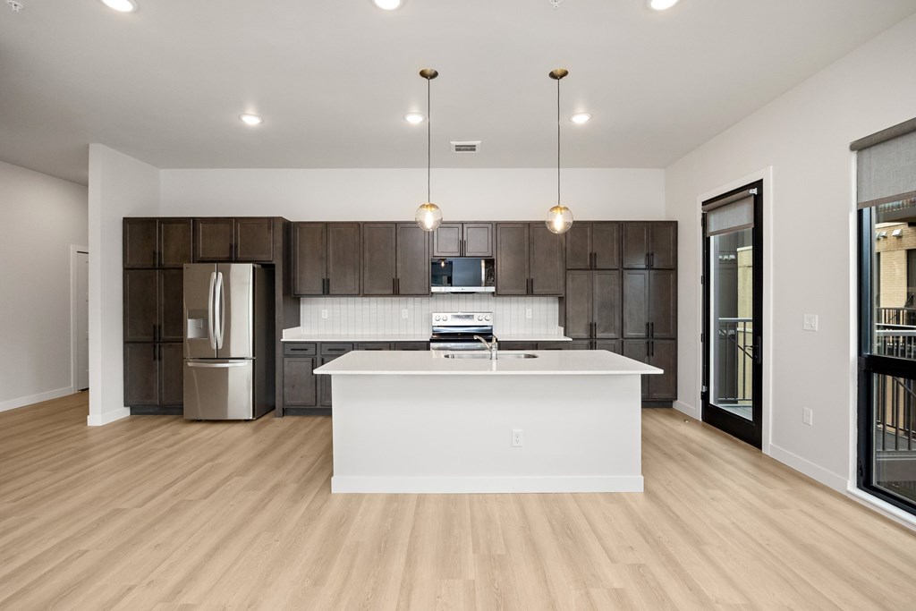 A modern kitchen with a white island and wooden floors.